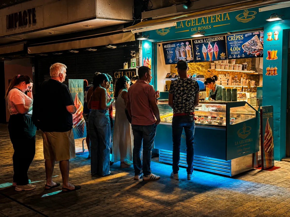 Fachada de La Gelateria de Roses de noche con clientes